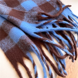 Close-up of blue and brown plaid scarf featuring soft texture and long tassel details