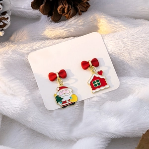 Close-up of Santa Claus and red house mismatched Christmas earrings with festive pine cones