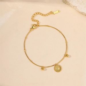 Minimalist gold stainless steel sunflower bracelet with small beads on a textured surface