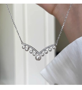 Macro detail of V-shaped zircon pendant with nine gradient pearls on a silver chain