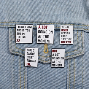Detail view of five enamel pins with lyrics pinned on a blue denim jacket pocket