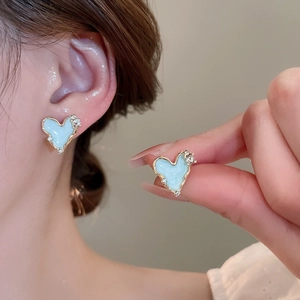 Detail of light blue heart earrings with golden lava edges and sparkling rhinestones