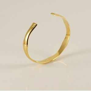 Detailed view of an 18K gold-plated stainless steel cuff with a polished bamboo-inspired design