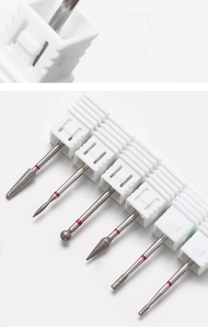 Macro shot of diamond nail drill bits with red ring markers on white plastic base