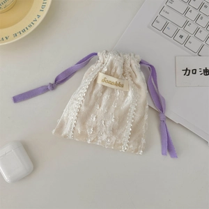 Detailed view of cream lace drawstring bag with purple cords and velvet texture