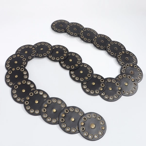 Detail of a punk style black belt featuring round leather discs with bronze metal eyelets
