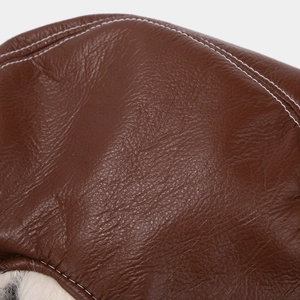 Detailed close-up of brown textured leather with white stitching and plush faux fur lining