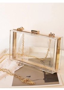 Detailed view of clear acrylic box bag with gold metal frame and secure latch closure