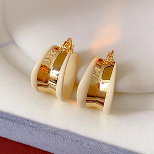 Gros plan de boucles d'oreilles en U plaquées or avec émail crème sur support blanc