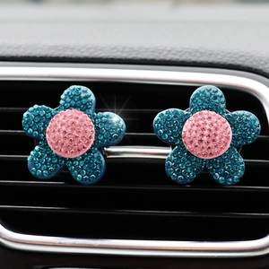 Close-up of blue and pink rhinestone flower car air vent clips on a vehicle outlet