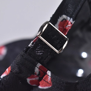 Macro detail of adjustable metal buckle and red rose print on a black baseball cap