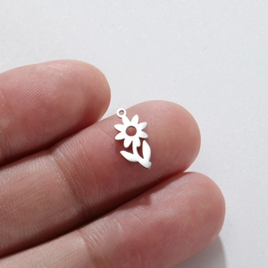 Macro shot of a small silver flower charm pendant for DIY jewelry on a fingertip