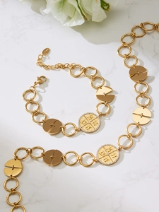 Macro shot of gold plated necklace and bracelet set with cubic zirconia on marble background
