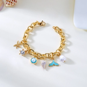 Detail view of gold ocean charms bracelet featuring starfish, seashell, and pearl pendants