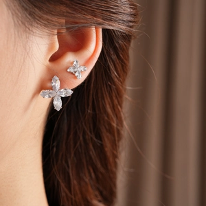 Gros plan de boucles d'oreilles fleur à quatre pétales et zircons sur un mannequin