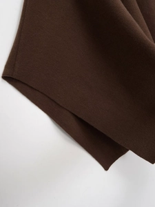 Macro detail of dark brown knit poncho fabric showing stitching and texture