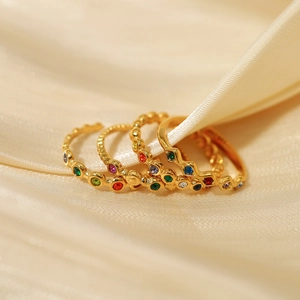 Set of four gold-plated stacking rings with colorful zircons on yellow silk background