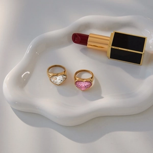 Detail shot of heart-shaped white and pink crystal rings in a white ceramic dish