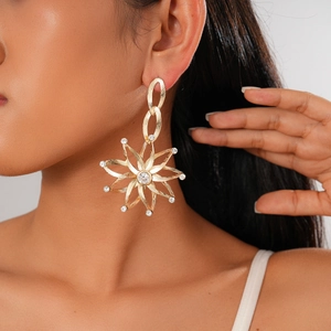 Detail of oversized gold starburst earrings with rhinestones worn by a model