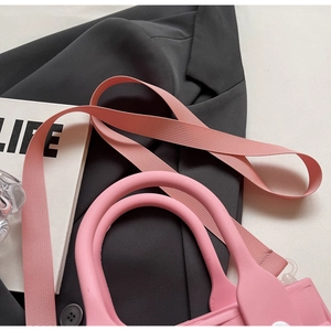 Detail of pink silicone handle and fabric shoulder strap on a trendy beach tote bag