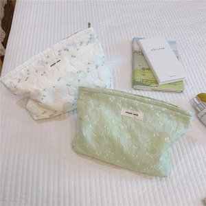 Detail shot of floral embroidery and texture on light green and white canvas pouch