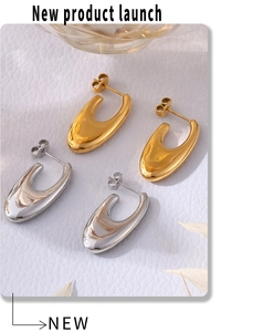 Close-up of polished gold and silver U-shape earrings on a white leather background