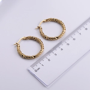 Detail view of gold hoop earrings with twisted texture and ruler for scale measurement