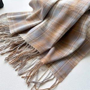 Detail of soft beige and light blue plaid scarf with elegant fringe trim texture