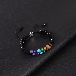 Detail of seven chakra energy stones and tree of life charm on woven bracelet