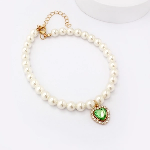 Detailed view of pearl pet collar with green heart gemstone pendant and gold clasp