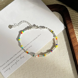 Detailed shot of colorful beaded bracelet with a central white pearl and heart charm