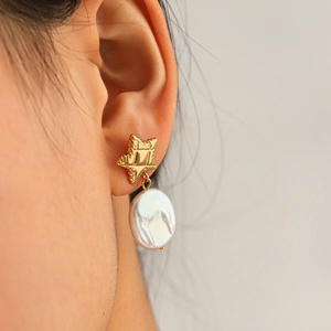 Boucles d'oreilles étoiles dorées avec perles d'eau douce sur un modèle féminin