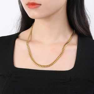 Detailed view of a gold Cuban link chain necklace worn on a model's neck