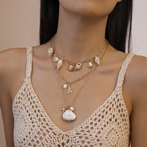 Gros plan d'un collier doré multicouche avec pendentifs coquillages et étoiles de mer