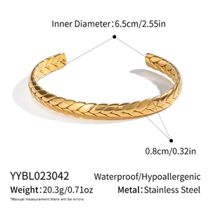 Dettaglio macro del motivo a spiga dorata su bracciale rigido in acciaio inossidabile