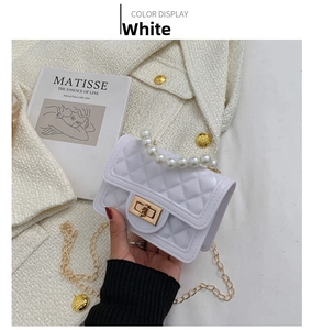 Detail of white glossy quilted bag with pearl handle and golden chain strap