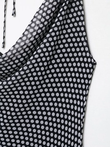 Detail of white polka dot print on black chiffon fabric showing the neckline structure