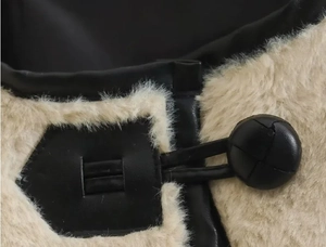 Détail macro d'une veste en fausse fourrure beige avec bordure en cuir noir et bouton