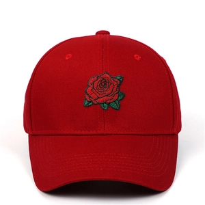 Gros plan sur une casquette en coton rouge avec broderie de rose détaillée devant