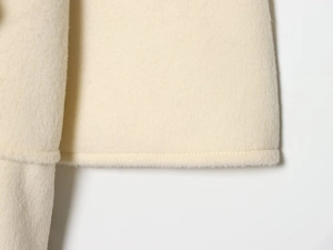 Detail shot of neat stitching and soft wool blend texture on the off-white coat hem