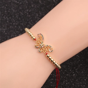Detailed shot of gold butterfly bracelet with colored zircons on red cord for women