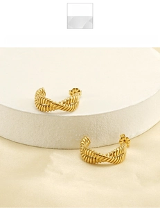 Detail of 18K gold plated twisted hoop earrings in titanium steel on silk fabric