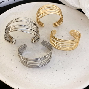 Detailed view of layered gold and silver open bangles with sleek minimalist design