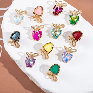 Colorful crystal bow pendants scattered on white stones for DIY jewelry making crafts