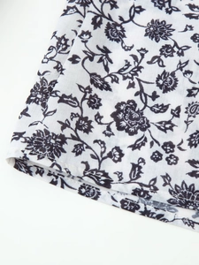 Détail du tissu blanc avec imprimés floraux noirs et finitions de couture d'ourlet