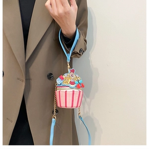 Detail of pink cupcake-shaped crossbody bag with gold chain and striped pattern