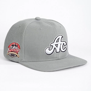 Grey flat-brim baseball cap with AC embroidery and sports badge shown in a 45-degree view