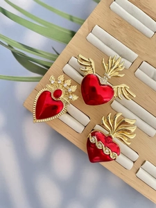 Detailed macro view of sacred heart brooches with red enamel wings and zircons