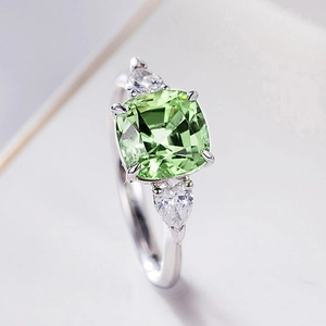 Anillo de lujo con esmeralda verde talla cojín y piedras laterales de pera en plata