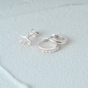 Macro detail of silver star stud and cz crystal paved huggie hoop earring set